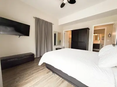 a bedroom with a white bed and a flat screen tv at Contemporary West Loft in Historic Niagara in Niagara on the Lake