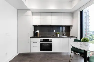 a kitchen with white cabinets and a table at Executive 1BR-1BA Condo in the heart of downtown in Toronto
