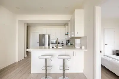 a kitchen with white cabinets and bar stools at The Residence, Your comfort is our culture in Oakville