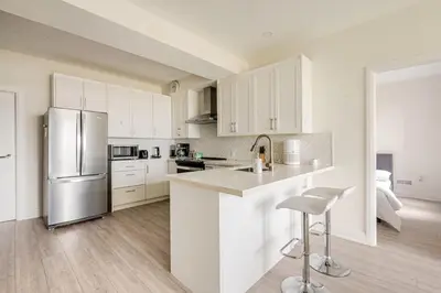 a kitchen with white cabinets and a stainless steel refrigerator at The Residence, Your comfort is our culture in Oakville