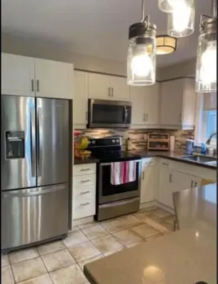 a kitchen with a stainless steel refrigerator and white cabinets at Serene Bedroom with Private Ensuite in Georgina
