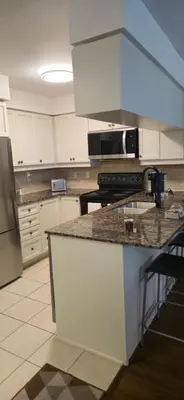 a kitchen with white cabinets and a granite counter top at Lovely condo near Lake Ontario in Toronto