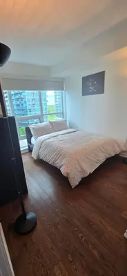 a bedroom with a bed and a large window at Lovely condo near Lake Ontario in Toronto