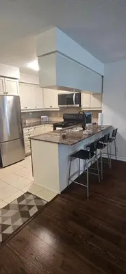 a kitchen with a counter with chairs and a refrigerator at Lovely condo near Lake Ontario in Toronto