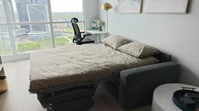 a bed and a chair in a room with a window at Reno'd Suite Steps to CN Tower - Free Parking in Toronto