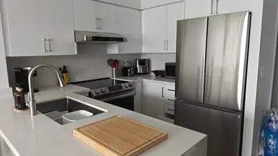 a kitchen with white cabinets and a stainless steel refrigerator at Reno'd Suite Steps to CN Tower - Free Parking in Toronto