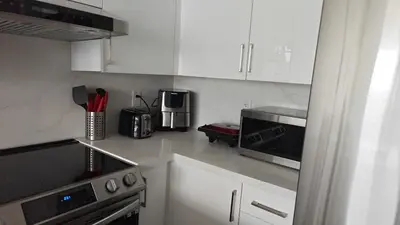 a kitchen with white cabinets and a microwave at Reno'd Suite Steps to CN Tower - Free Parking in Toronto