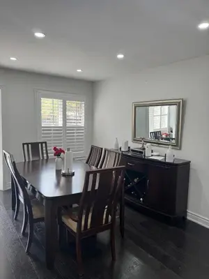 a dining room with a table and chairs and a mirror at Pearson Gateway Comfort Home in Mississauga