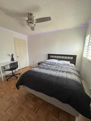 a bedroom with a bed and a desk and a ceiling fan at Pearson Gateway Comfort Home in Mississauga