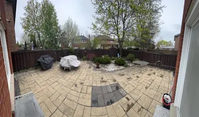 a backyard with a stone patio with a fence at Pearson Gateway Comfort Home in Mississauga