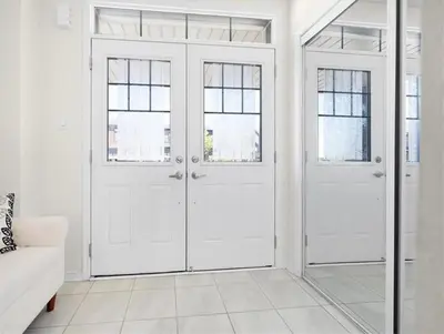 a white living room with two doors and a couch at Classy Home Near Beach & Airport in Hagersville