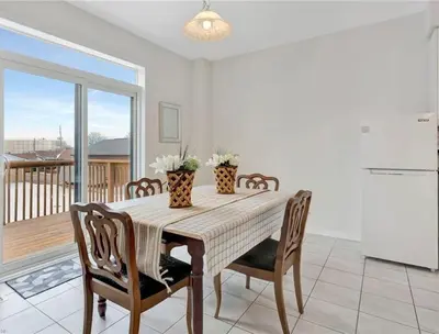 a dining room with a table and chairs and a balcony at Classy Home Near Beach & Airport in Hagersville
