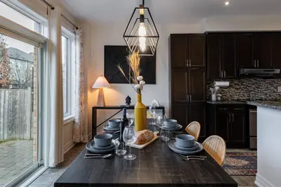 a dining room with a wooden table and a kitchen at Family Retreat. in Milton