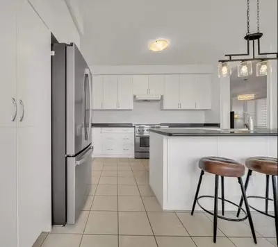a kitchen with a refrigerator and two bar stools at Cambridge Luxury by Ravine in Cambridge