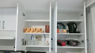 a white pantry with plates and dishes on shelves at Beautiful Studio with Patio in Mississauga in Mississauga