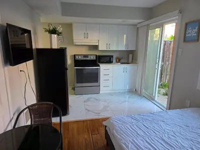 a kitchen with white cabinets and a black refrigerator at Beautiful Studio with Patio in Mississauga in Mississauga