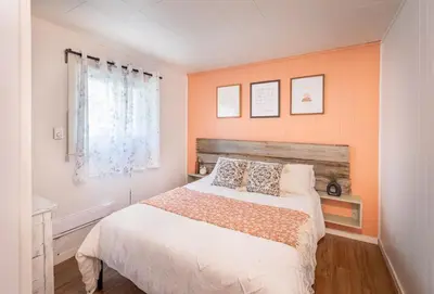 a bedroom with a bed with orange walls and a window at Hills Haven - Luxury Riverfront Cottage in Minden
