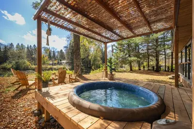 a hot tub in a wooden deck with a pergola at Hills Haven - Luxury Riverfront Cottage in Minden