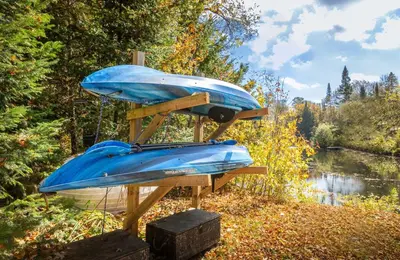 a blue boat on a stand next to a river at Hills Haven - Luxury Riverfront Cottage in Minden