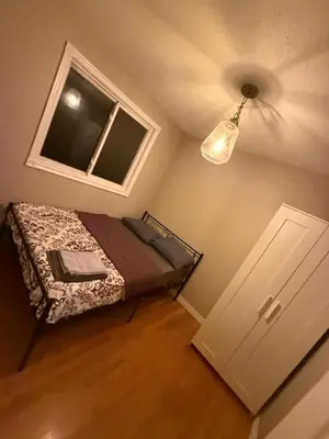 a small bedroom with a bed and a window at Homestay at Heart Of Kitchener-Free Wifi & Parking in Kitchener