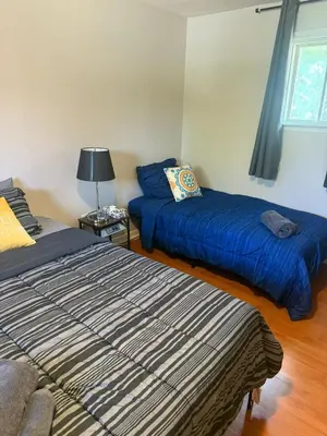 a bedroom with two beds with blue sheets and a lamp at \u9a6c\u5361\u59c6\u7684\u5bc4\u5bbf\u5bb6\u5ead- Simple Trip To Toronto in Markham