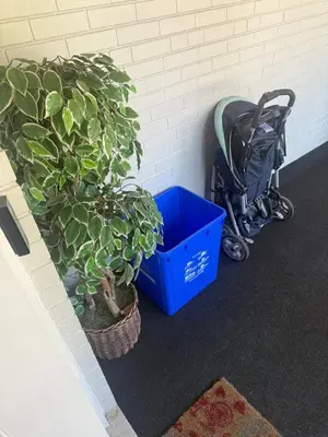 a stroller and a blue crate next to a wall with plants at \u9a6c\u5361\u59c6\u7684\u5bc4\u5bbf\u5bb6\u5ead- Simple Trip To Toronto in Markham