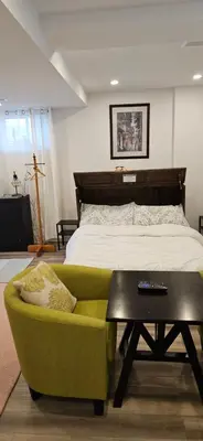a bedroom with a bed and a green chair and a table at Walk out Basement Studio in Smithville