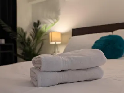 a pile of towels sitting on top of a bed at The Urban Hideaway - Stylish Stay - Prime Spot in Hamilton