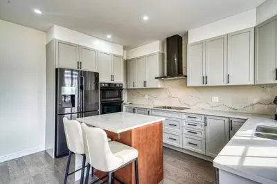a kitchen with white cabinets and a kitchen island with stools at Youngs Cove Chalet in Prince Edward County in Carrying Place