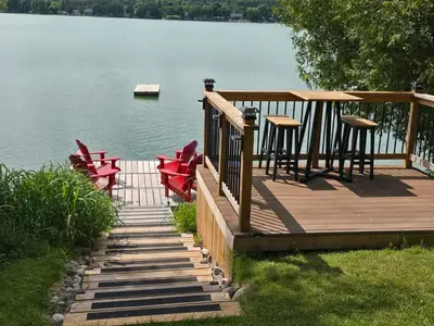 a wooden deck with chairs and tables on the water at Lovely Little Lake House in Brighton