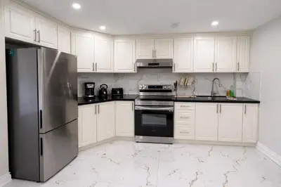 a kitchen with white cabinets and a stainless steel refrigerator at Newly Renovated 3BR Orangeville Basement Suite with Private Access, 10 Min Walk to Headwaters Hospital, 5 Min Drive to Mount Alverno! Ideal for Medical Stay, Family Travel & Work Trips! in Orangeville