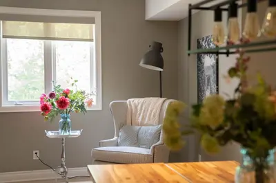 a living room with a chair and a vase of flowers at Cozy Private Suite with Year-Round Hot Tub in Elora