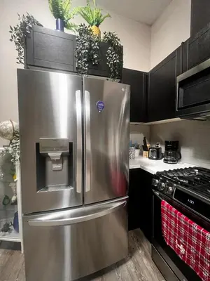 a stainless steel refrigerator in a kitchen with black cabinets at Downtown Private Room Central Location in Toronto