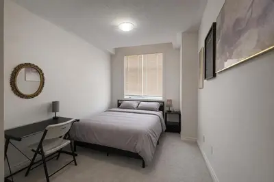 a bedroom with a bed and a desk and a window at 2024 Built Stylish 3BR Cambridge Townhouse with Free Parking, WiFi, Full Kitchen, Laundry, 8 Min Drive to African Lion Safari! Perfect for Family Travel, Group Trips & Work Stays! in Cambridge
