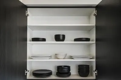 a pantry with black bowls and plates on shelves at 2024 Built Stylish 3BR Cambridge Townhouse with Free Parking, WiFi, Full Kitchen, Laundry, 8 Min Drive to African Lion Safari! Perfect for Family Travel, Group Trips & Work Stays! in Cambridge