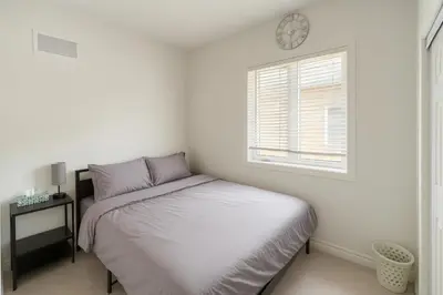 a white bedroom with a bed and a window at 2024 Built Stylish 3BR Cambridge Townhouse with Free Parking, WiFi, Full Kitchen, Laundry, 8 Min Drive to African Lion Safari! Perfect for Family Travel, Group Trips & Work Stays! in Cambridge