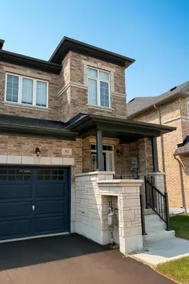 a brick house with a blue garage door at 2024 Built Stylish 3BR Cambridge Townhouse with Free Parking, WiFi, Full Kitchen, Laundry, 8 Min Drive to African Lion Safari! Perfect for Family Travel, Group Trips & Work Stays! in Cambridge