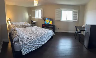 a bedroom with a bed and a desk and two windows at Master bedroom suite on the 2nd floor, city center in Mississauga
