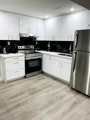 a kitchen with white cabinets and a stainless steel refrigerator at Cozy 2 Bedroom Apartment in Brampton in Brampton