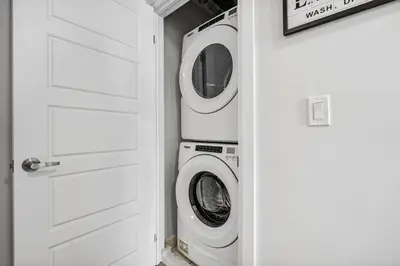 a washer and dryer in a laundry room with a door at Stunning 2BR Toronto Retreat, Patio & Parking in Toronto