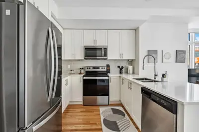 a kitchen with white cabinets and a stainless steel refrigerator at Stunning 2BR Toronto Retreat, Patio & Parking in Toronto