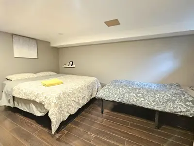 a bedroom with two beds and a bench in it at Downtown Queen and King St - Lower Suite in Toronto