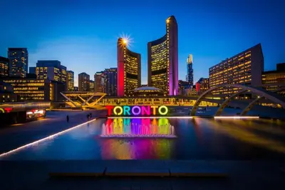 a city skyline at night with a neon sign in the water at Downtown Queen and King St - Lower Suite in Toronto