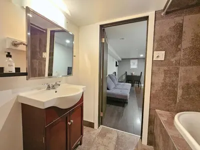 a bathroom with a sink and a mirror and a couch at Downtown Queen and King St - Lower Suite in Toronto
