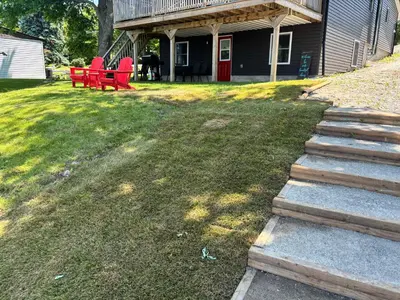 a yard with red chairs and a house at Rice Lake Retreat in Roseneath