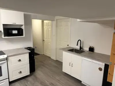 a kitchen with white cabinets and a sink and a stove at Rice Lake Retreat in Roseneath