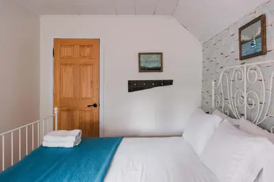 a bedroom with a white bed and a wooden door at The County Queen - Historic Home in Picton in Picton