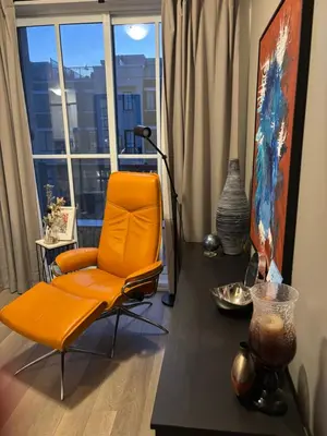 a living room with an orange chair and a table at Beautiful Quaint Home in Port Credit, Mississauga in Mississauga