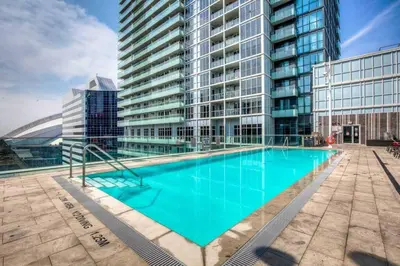 a large swimming pool in front of a tall building at Downtown CN Tower View Condo with Pool Hot tub and Gym in Toronto