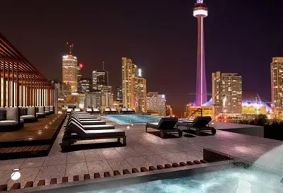 a rooftop pool with a view of a city at night at Downtown CN Tower View Condo with Pool Hot tub and Gym in Toronto